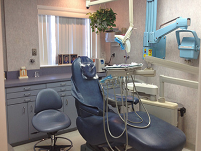 The image shows a dental office with a chair, dental equipment, a sink, and a window.