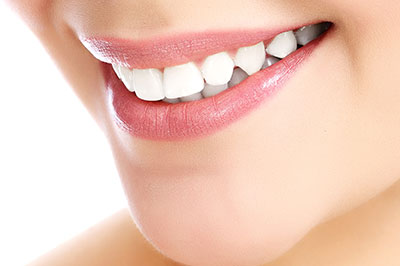 The image shows a close-up of a person s face with a focus on their teeth, which are being highlighted by a bright smile.