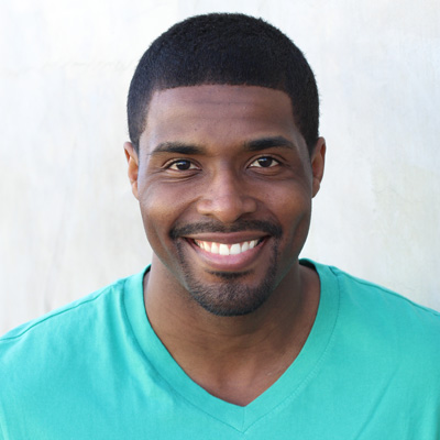 An elderly couple sharing a warm embrace, smiling at the camera against a backdrop of a serene outdoor setting.