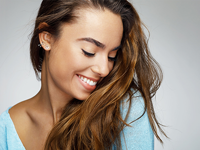 A woman with long brown hair smiles gently at the camera against a white background.