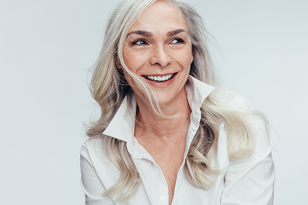 The image shows a woman with short blonde hair smiling at the camera.