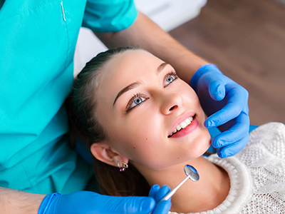 A dental hygienist is performing a teeth cleaning procedure on a woman s mouth, with a focus on the dental instruments and the patient s smile.